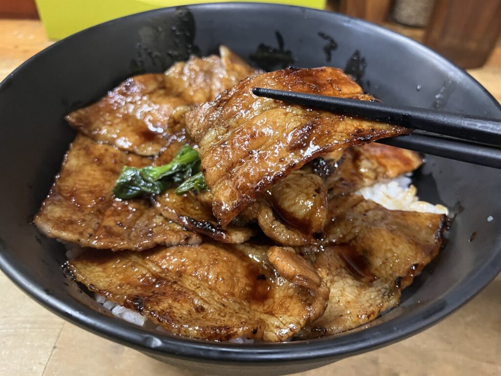 箸で持ち上げた豚バラ肉とその下の白ご飯