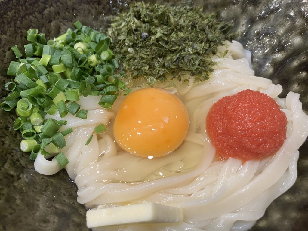 やや平らな麺に卵黄・明太子・バター・海苔がのった様子
