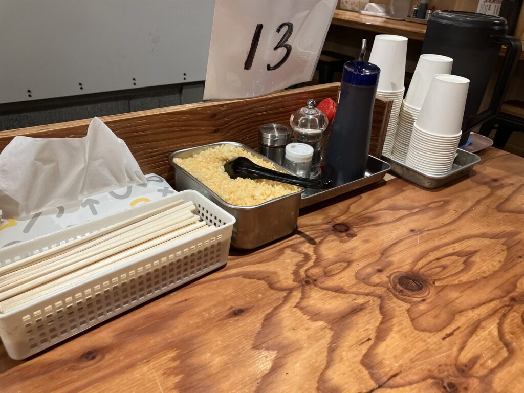 カウンターに置かれた天かすや醬油などの卓上調味料