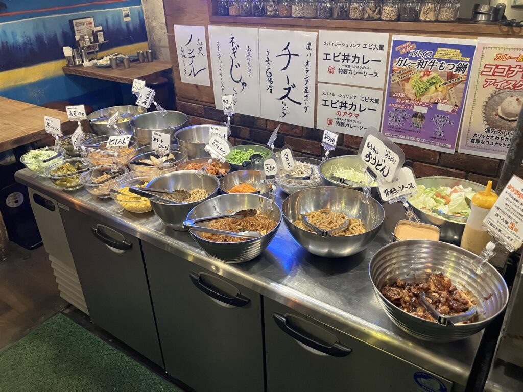 うどんや高菜、コーンなどが並ぶトッピングコーナー