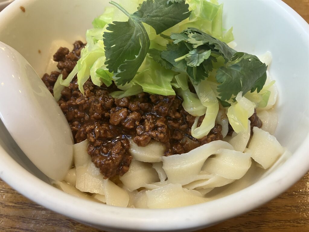 炸醤刀削麺にのせられたパクチーとキャベツ